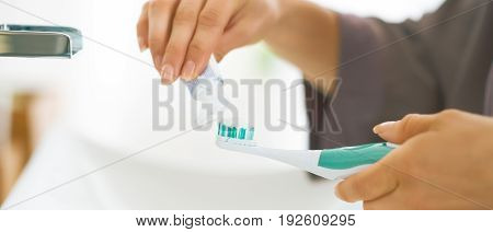 Closeup On Young Woman Squeezing Toothpaste On Toothbrush