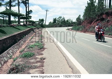 A narrow road in the mountains of Vietnam along which people ride motorbike. With toning.