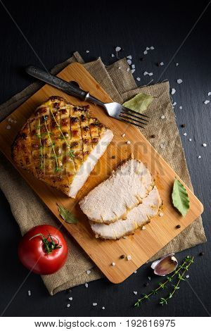 Roasted and sliced pork carbonade glazed with honey and mustard on wooden cutting board and stone surface