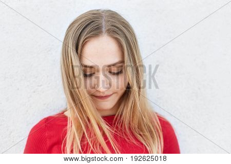 Close Up Of Pensive Woman With Fair Hair Wearing Red Sweater Looking Down Having Some Thoughts In He