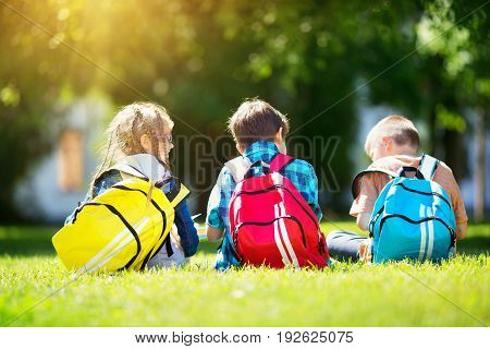 Children with rucksacks standing in the park near school. Pupils with books and backpacks outdoors