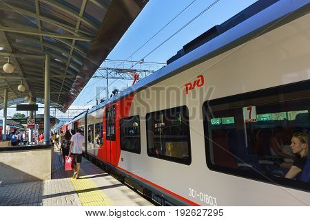 Sochi Krasnodar Krai Russia - June 09.2017: Passengers walk along the platform past the commuter trains at the railway station of Sochi Sunny day