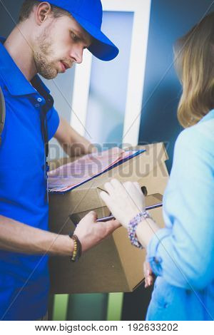 Smiling delivery man in blue uniform delivering parcel box to recipient - courier service concept