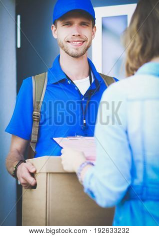 Smiling delivery man in blue uniform delivering parcel box to recipient - courier service concept