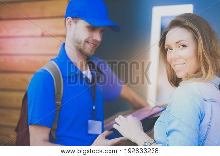 Smiling delivery man in blue uniform delivering parcel box to recipient - courier service concept
