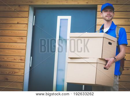 Smiling delivery man in blue uniform delivering parcel box to recipient - courier service concept