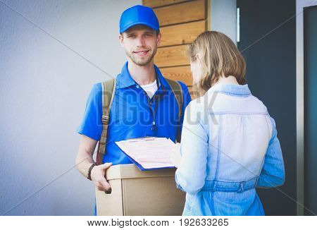 Smiling delivery man in blue uniform delivering parcel box to recipient - courier service concept
