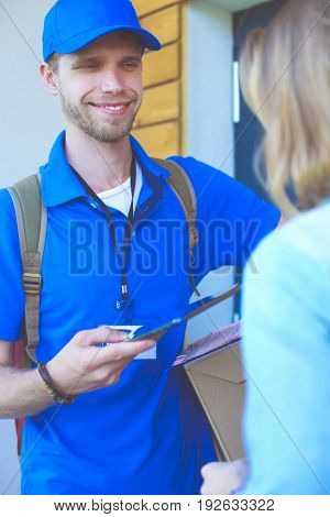 Smiling delivery man in blue uniform delivering parcel box to recipient - courier service concept