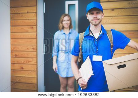 Smiling delivery man in blue uniform delivering parcel box to recipient - courier service concept
