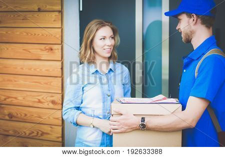 Smiling delivery man in blue uniform delivering parcel box to recipient - courier service concept