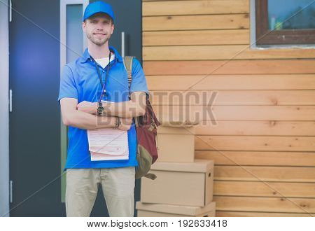 Smiling delivery man in blue uniform delivering parcel box to recipient - courier service concept