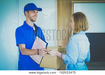 Smiling delivery man in blue uniform delivering parcel box to recipient - courier service concept