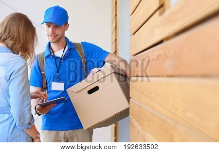 Smiling delivery man in blue uniform delivering parcel box to recipient - courier service concept