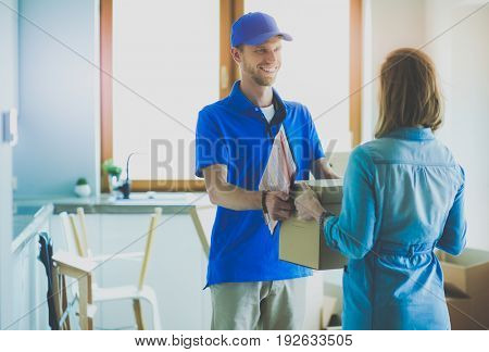 Smiling delivery man in blue uniform delivering parcel box to recipient - courier service concept