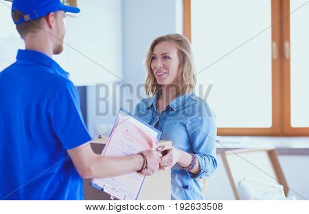 Smiling delivery man in blue uniform delivering parcel box to recipient - courier service concept