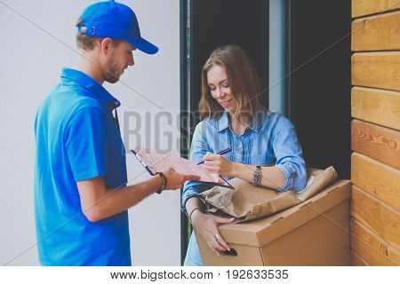 Smiling delivery man in blue uniform delivering parcel box to recipient - courier service concept