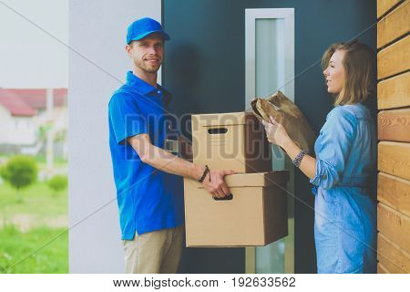 Smiling delivery man in blue uniform delivering parcel box to recipient - courier service concept