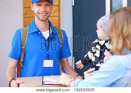 Smiling delivery man in blue uniform delivering parcel box to recipient - courier service concept