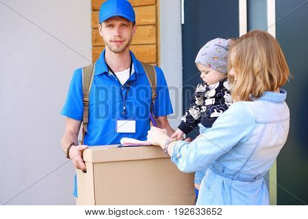 Smiling delivery man in blue uniform delivering parcel box to recipient - courier service concept