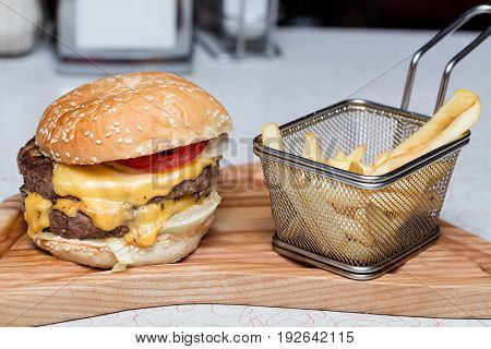 Burger with fresh tomato, cheese, meat and french fries.