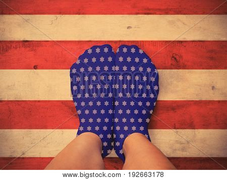 Selfie feet wearing blue socks with white star shape on wooden red and white floor background vintage filter effect. American flag and 4th of July concept.