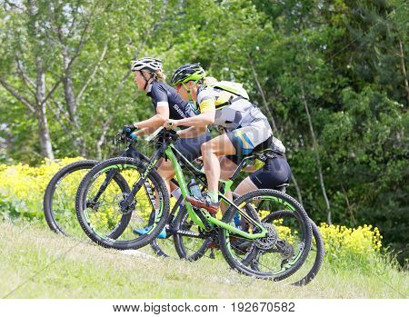 STOCKHOLM SWEDEN - JUNE 11 2017: Three female mountain bike cyclists cycling uphill at Lida Loop Mountain bike Race. June 11 2017 in Stockholm Sweden