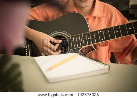 girl student compose song in notebook and playing guitar in school