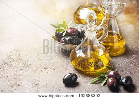 Olive oil in a glass bottle and olive branch on brown stone table