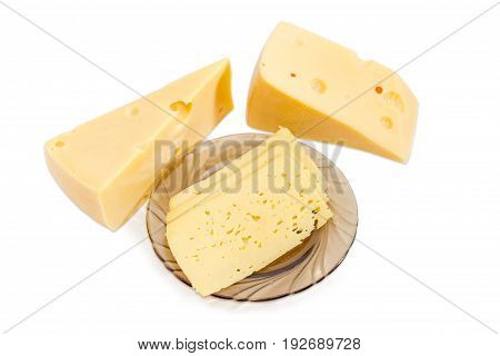 Semi-hard cheese cut into thin rectangular slices on the dark glass saucer and two pieces of the Swiss-type cheese beside on a light background