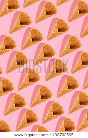 Sugar waffle cone for ice cream arranged in pattern on pink background. The image with copy space can be used as a background for the design of the confectionery menu, cards, greetings, invitations, pattern