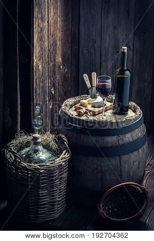 Red Wine With Cheese And Demijohn In Basement