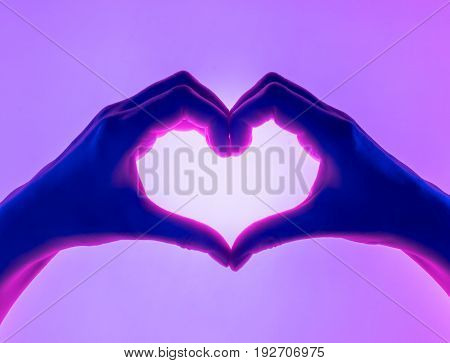 Hands in the form of heart violet background. heart symbol with hand. valentines day card. Woman's hands silhouette in form of heart. hand Gestures
