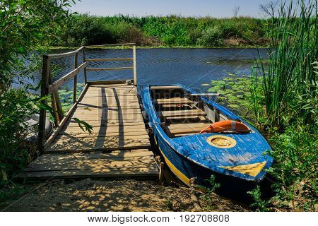 The moored boat on the shore of the pond. Boating services.