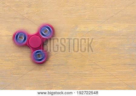 Closeup a new red fidget spinner on a yellow wooden background