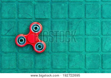 Top view of the popular red spinner gadget in 2017 on the blue-green background