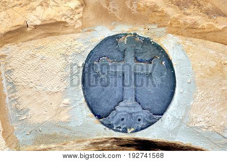 Stone cross hanging on a stone wall, background.