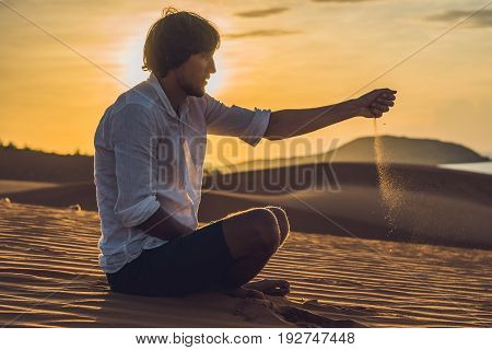 A Man Is Pouring Sand In The Desert. Sand Through The Fingers Of The Concept