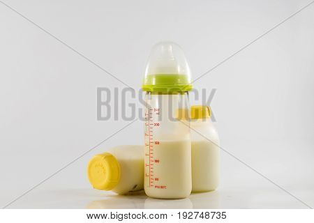 Baby bottle with milk and a measuring scale on the background of a lot of full bottles of breast milk. Mother's milk - the most healthy food for newborn