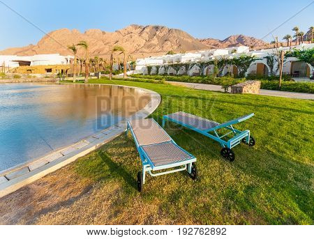 Egypt Dahab - hotel swimming pool with sea water and sun loungers. Early morning