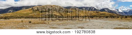 Middle Earth New Zealand - March 14 2017: Panorama shot of the Rock of Middle Earth with surrounding mountains set in a high desert scenery under blue cloudy sky.