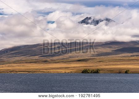 Middle Earth New Zealand - March 14 2017: Landscape with focus on Volcano Potts behind blue Lake Clearwater. All under blue cloudy sky.