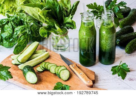 Detox diet. Two small bottles of fresh green smoothies with ingredients on a light wooden background