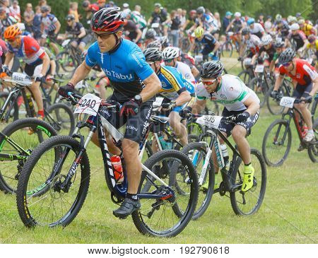 STOCKHOLM SWEDEN - JUNE 11 2017: Side view of group of fighting male mountain bike cyclists cycling uphill at Lida Loop Mountain bike Race audience in background. June 11 2017 in Stockholm Sweden