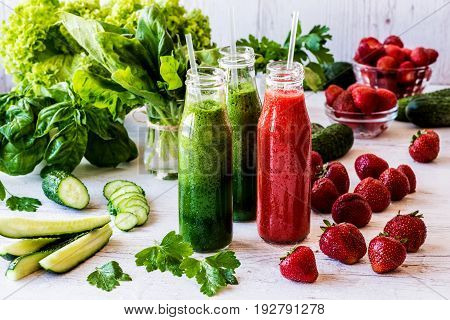 Fresh green smoothies and strawberry smoothie with ingredients on a light wooden background. Healthy detox drinks