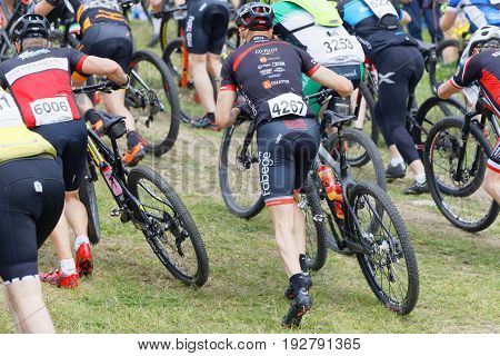 STOCKHOLM SWEDEN - JUNE 11 2017: Group of male mountain bike cyclists running with cycles uphill at Lida Loop Mountain bike Race. June 11 2017 in Stockholm Sweden