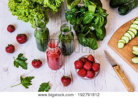 Fresh green smoothies and strawberry smoothie with ingredients on a light wooden background. Healthy detox drinks