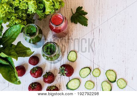 Top view. Fresh green smoothies and strawberry smoothie with ingredients on a light wooden background. Healthy detox drinks