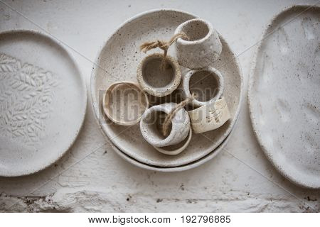 Top view on three grog clay plates with beautiful rustic napkin rings on white background