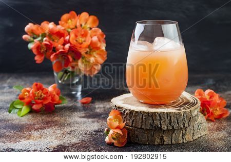 Floral pastel peach and pink brunch cocktail garnished with quince flowers over old rustic background.
