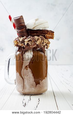 Chocolate indulgent exreme milkshake with brownie cake marshmallow and sweets. Crazy freakshake food trend. Copy space